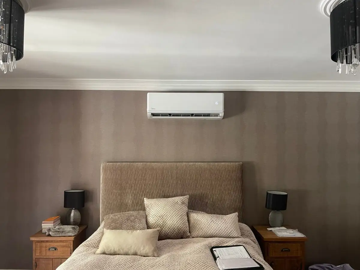 Wall-mounted air conditioner installed above the bed in a Manchester guest bedroom