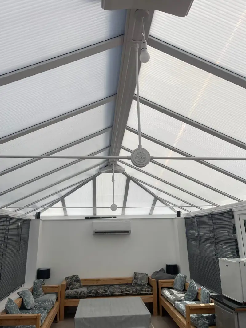 Wall-mounted air conditioning unit in a glass-roof conservatory