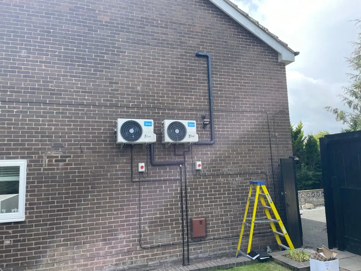 Two compact outdoor air conditioning units installed side by side on a brick wall