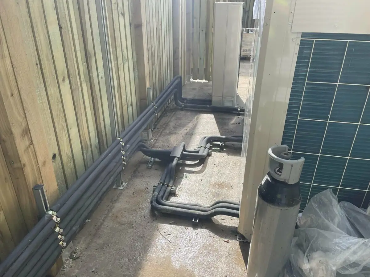 Insulated refrigerant pipework inspected for leaks along a commercial building